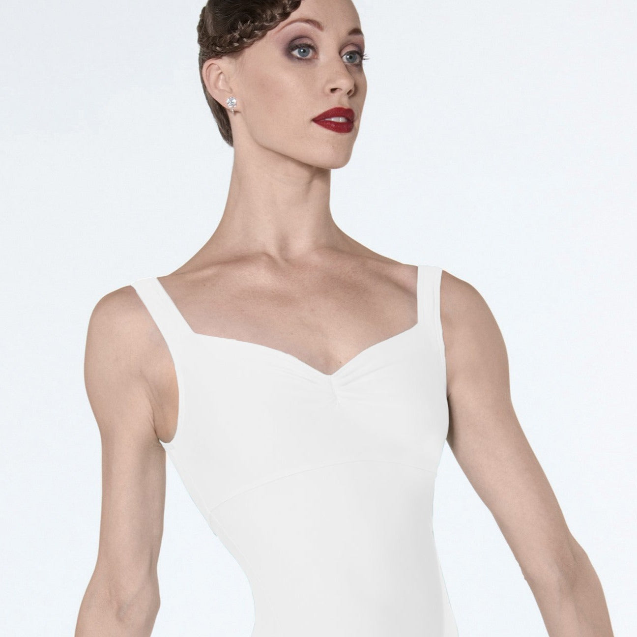 A female model wearing a white microfiber pinch front tank leotard with under bust detail.