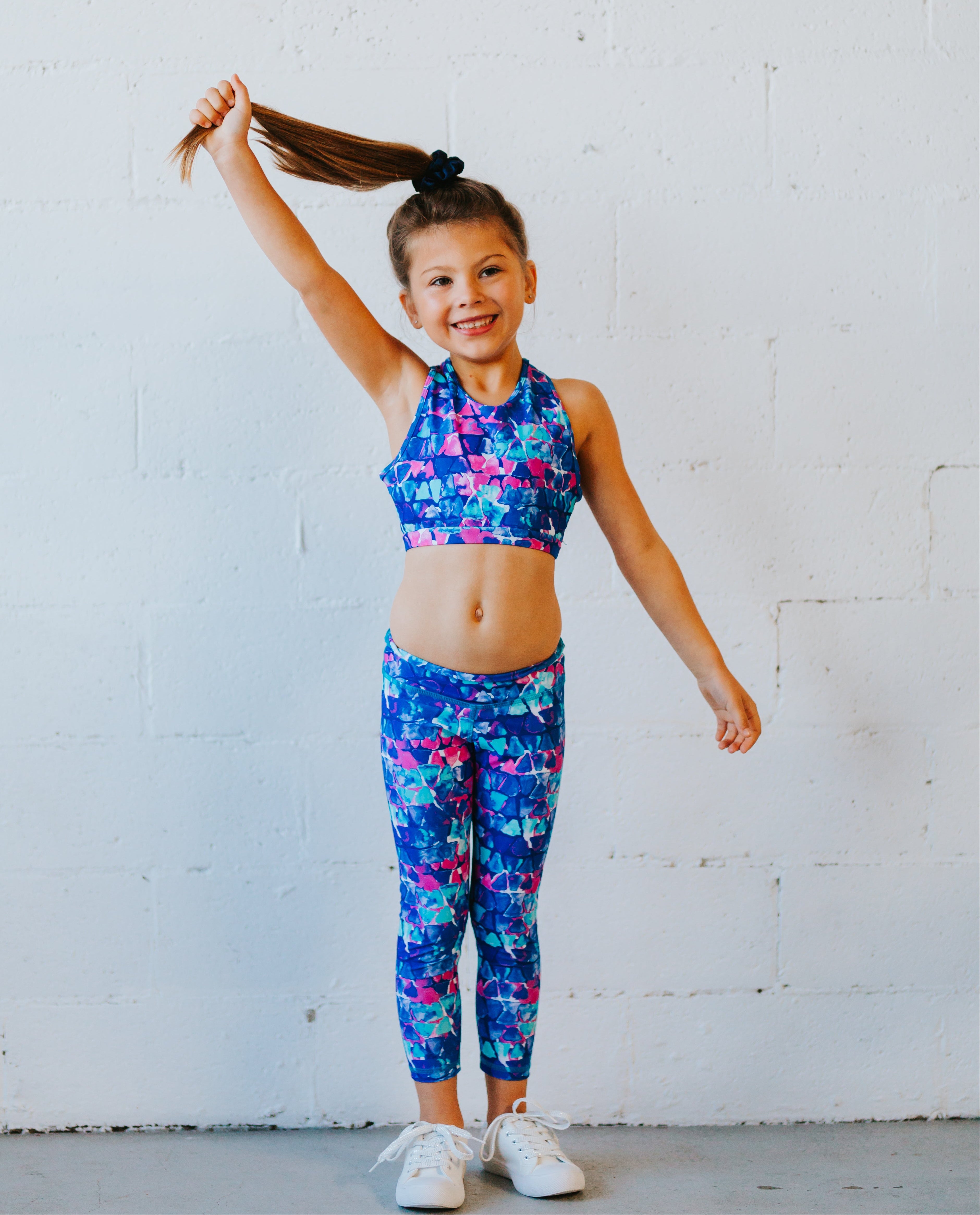 Young girl in colorful sports outfit posing against a white wall