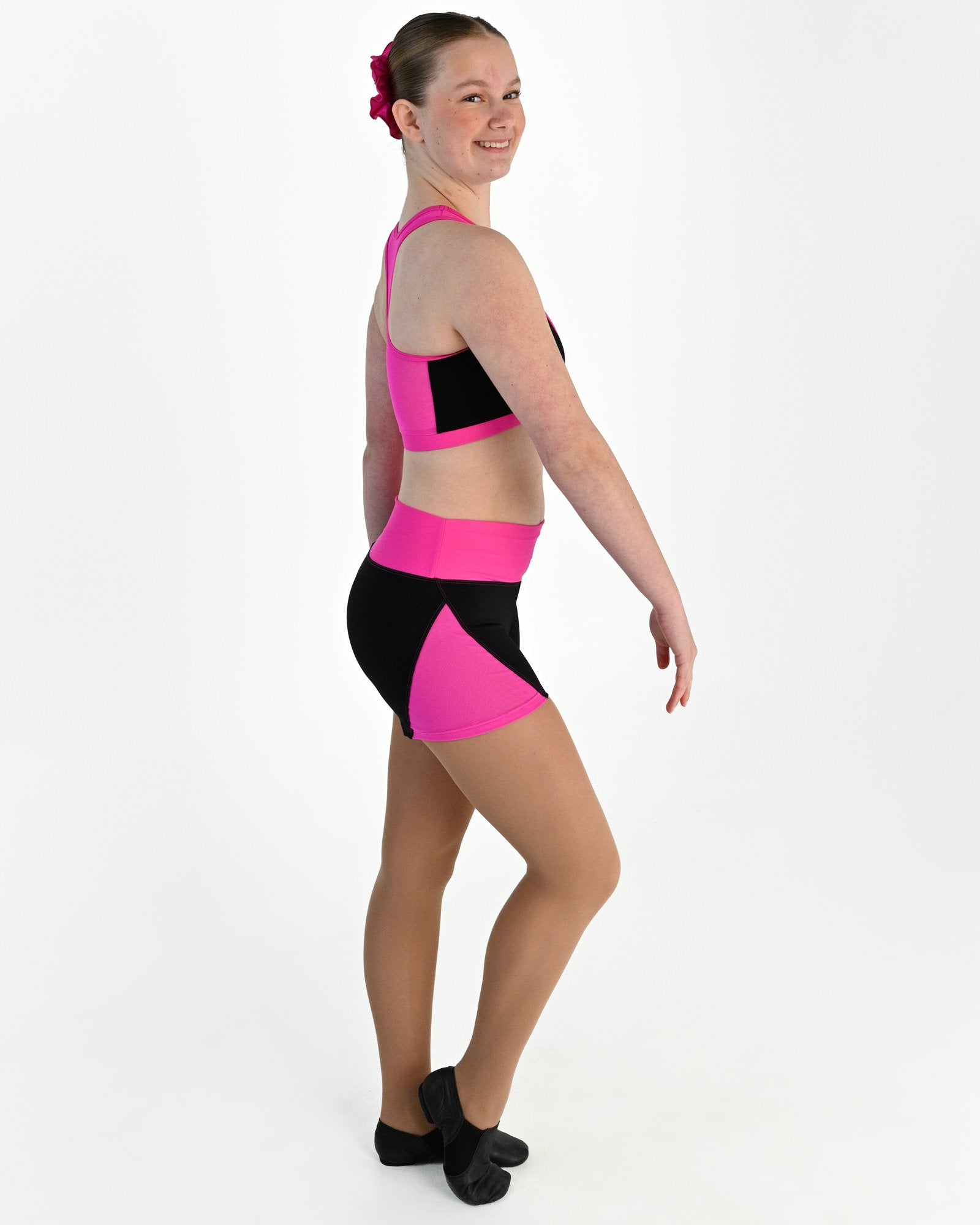 Young dancer wearing the Electra mesh panel high waisted dance shorts in Electric Pink, alternate view