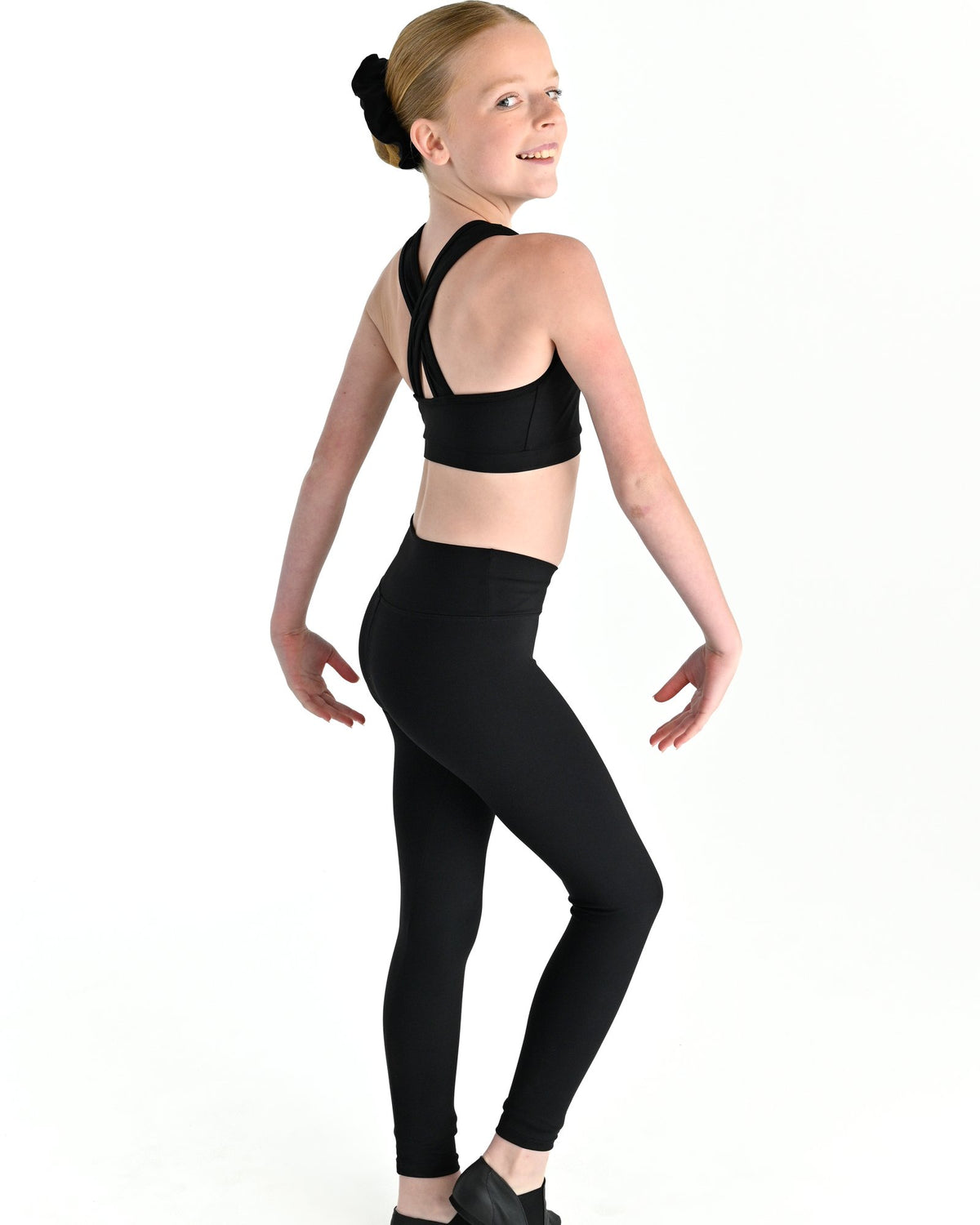 Young dancer wearing the Violet crossed back dance crop top with contrast binding in Black, alternate view