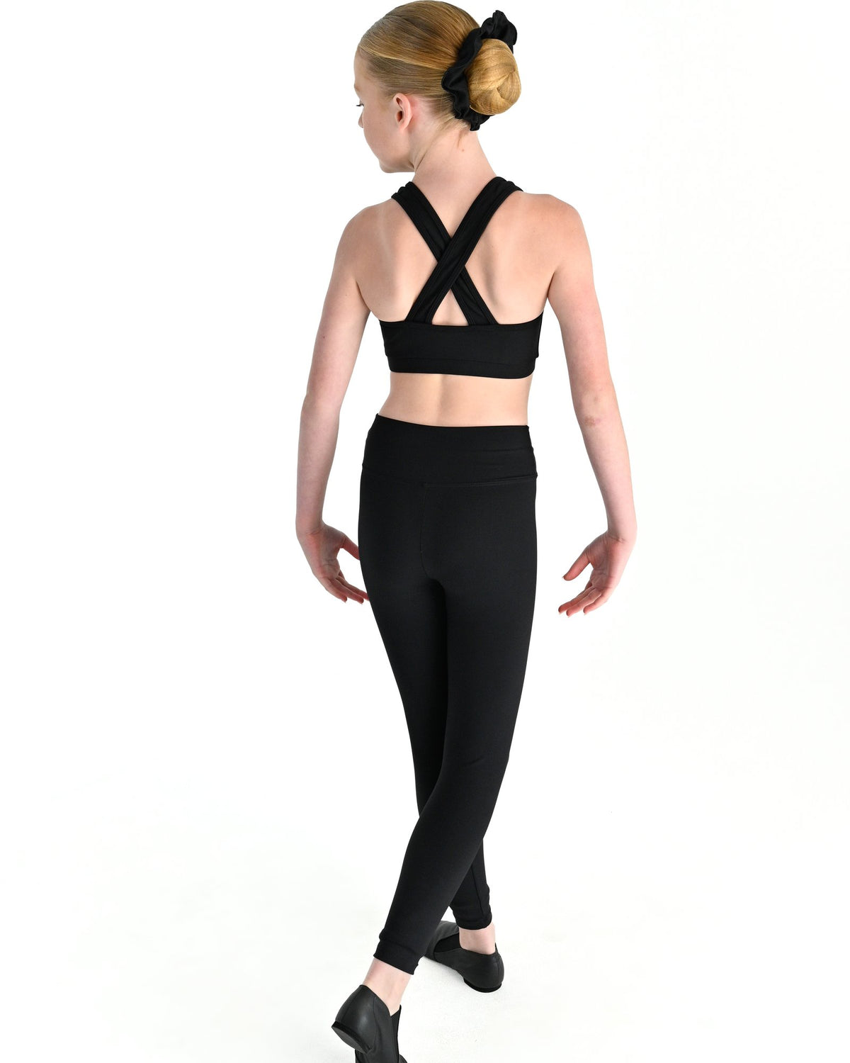 Young dancer wearing the Violet crossed back dance crop top with contrast binding in Black, alternate view
