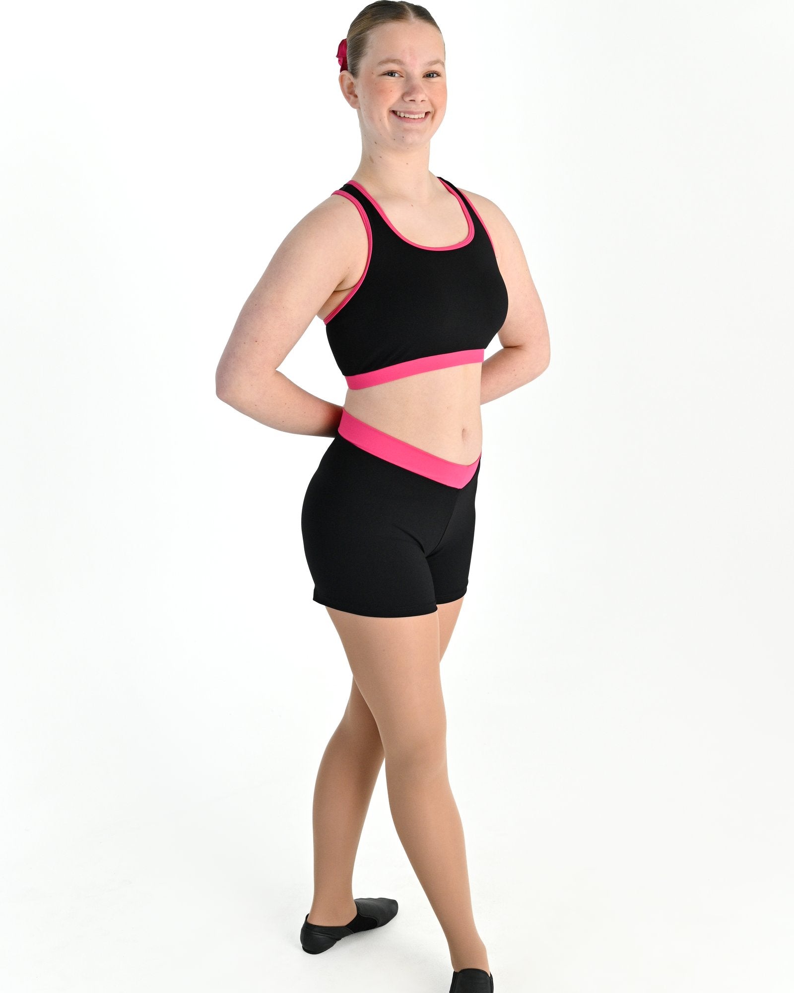 Young dancer wearing the Violet crossed back dance crop top with contrast binding in Hot Pink