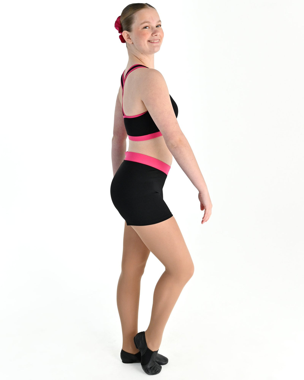 Young dancer wearing the Violet crossed back dance crop top with contrast binding in Hot Pink, alternate view