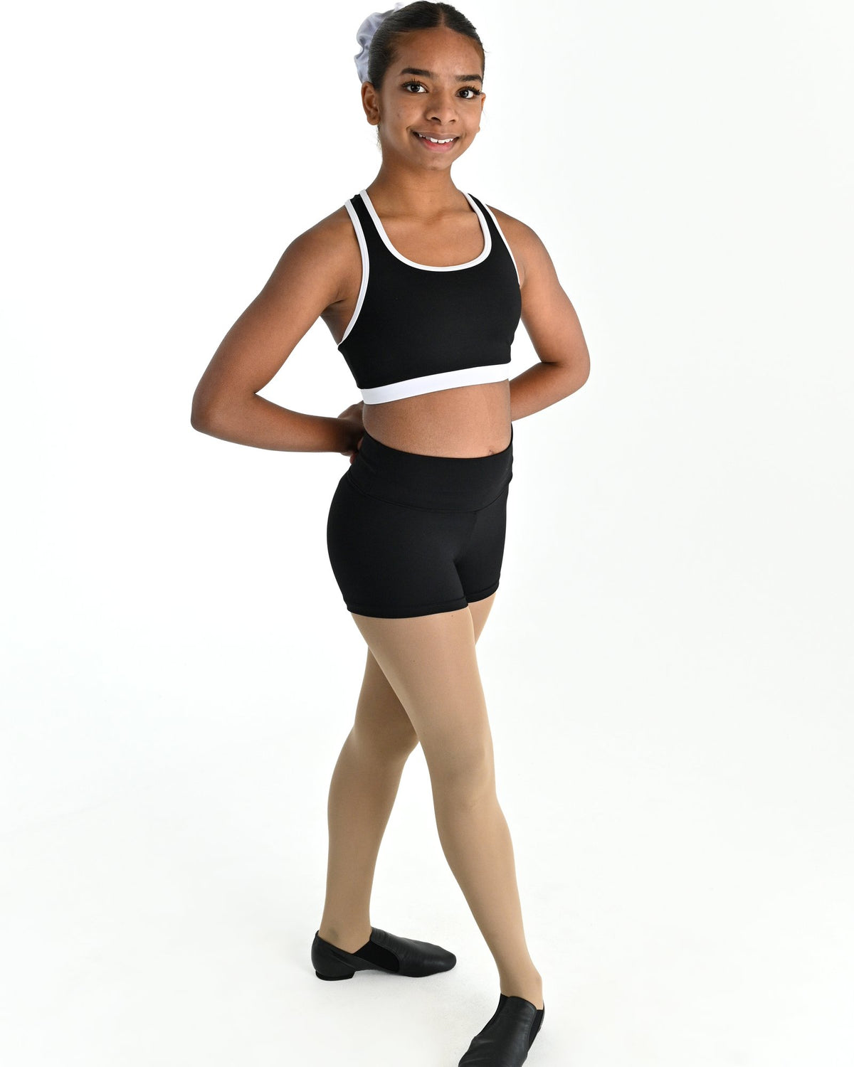 Young dancer wearing the Violet crossed back dance crop top with contrast binding in White